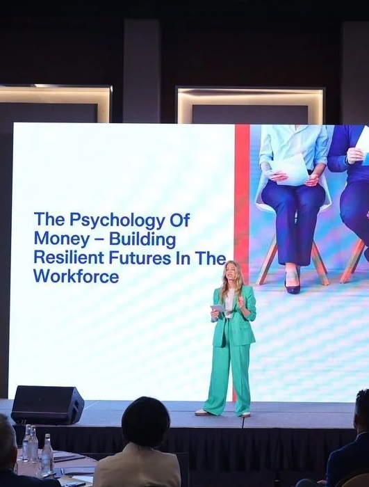 Beth Clay on stage presenting The Psychology of Money to a corporate audience